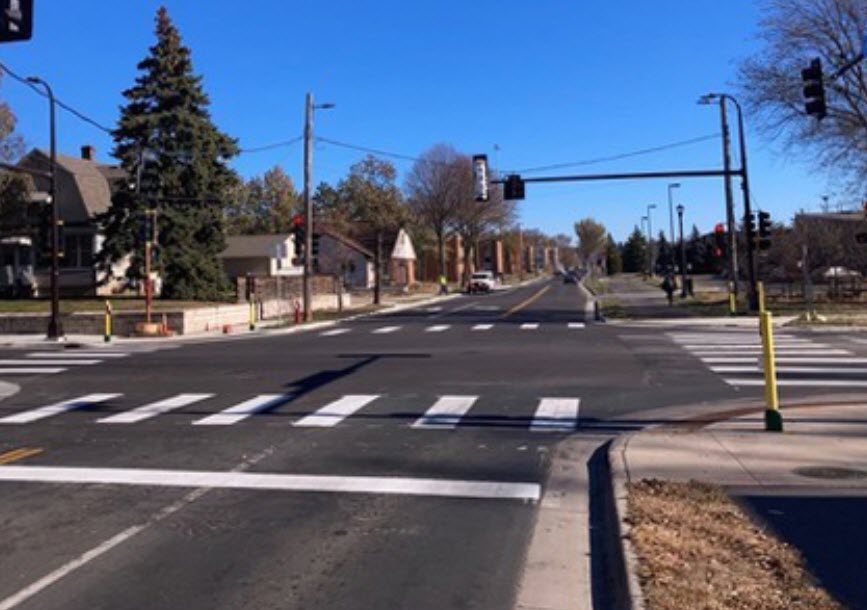 Paved intersection with crisp white paint and hanging traffic light