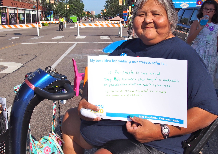 Person on assisted mobile device holding sign on their idea for having safe streets Text available in the caption due to character limitation.