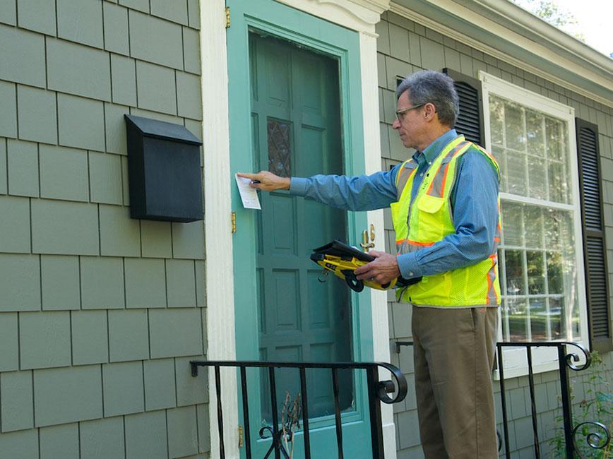 Person in yellow vest ringing doorbell
