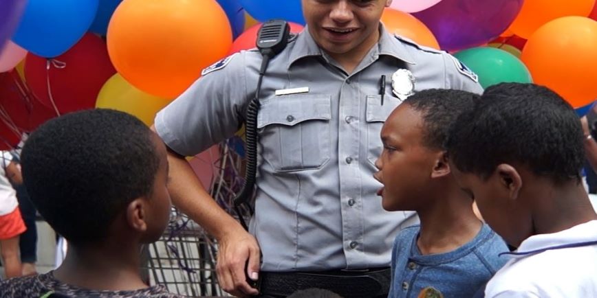 Community service officer with kids and balloons.