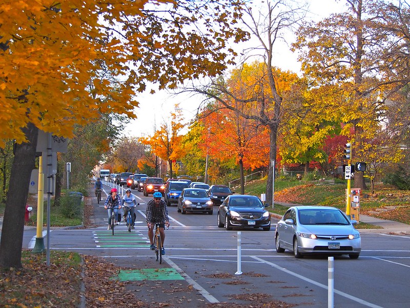 A group of bicyclists ride in a protected bike lane.