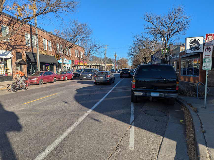 Two way street view with a bike lane and parking on the right