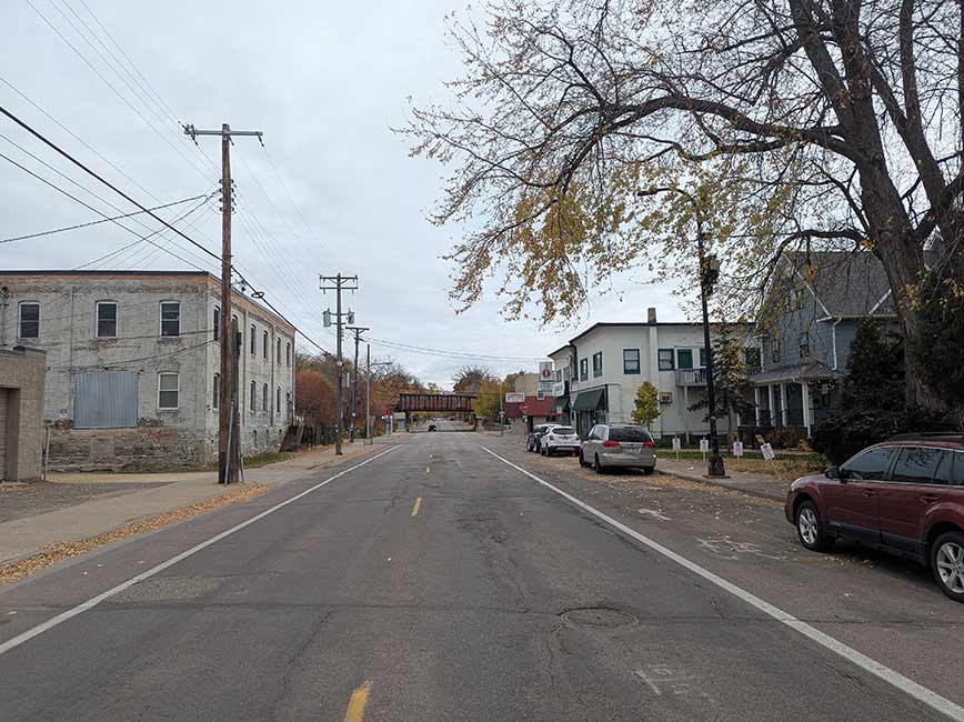 Two way street with tree on right and building on left