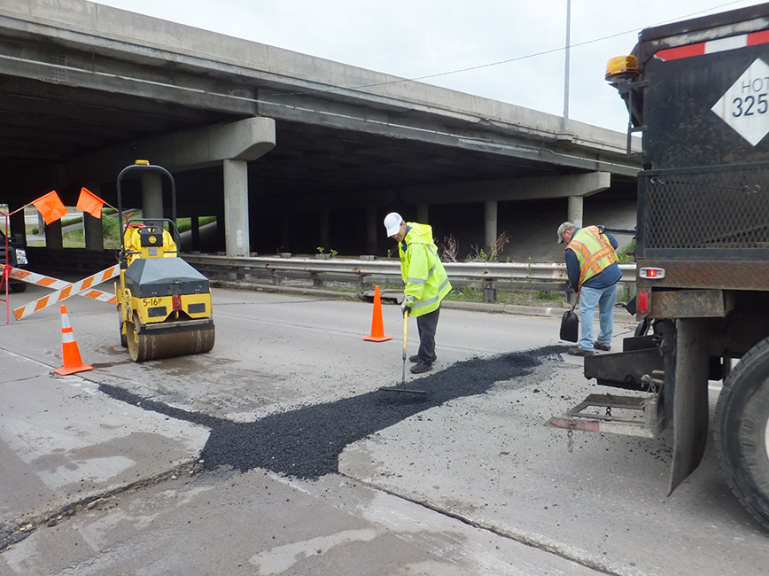 A crew fills a pothole in a road.
