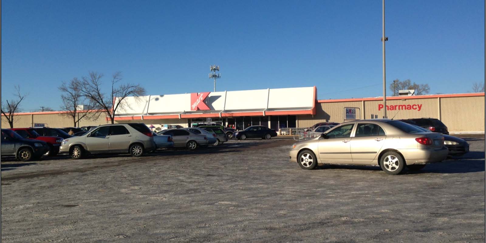 Looking at front exterior of former Kmart on Nicollet; parking lot and cars in foreground.