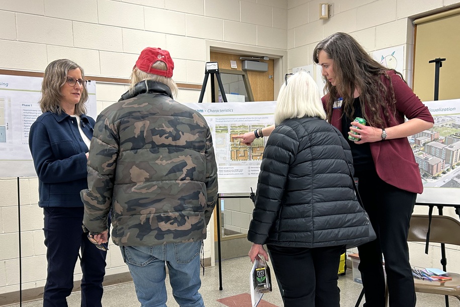 Four people gathered around display boards discussing the plans