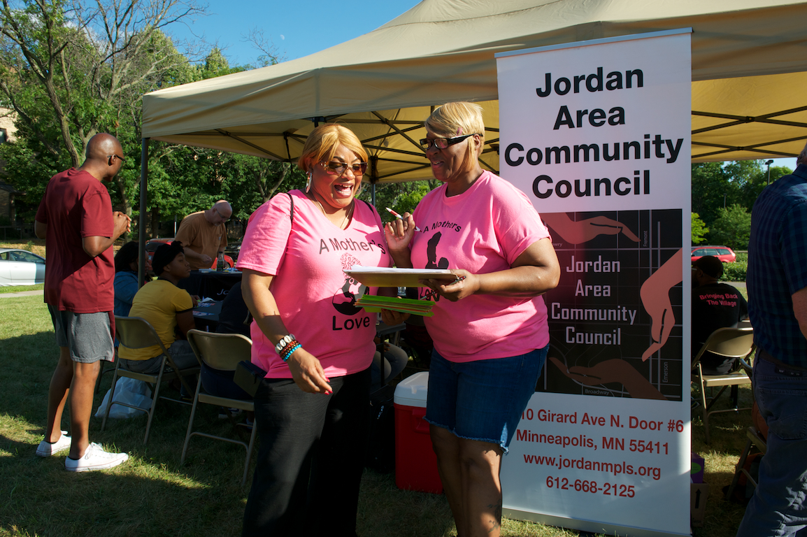 Two women talking at Jordan Area Community Council tent