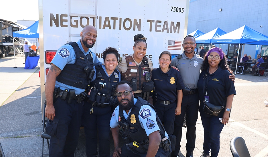 Group of police officers posing for a picture outside at community event