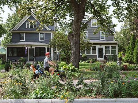 Riding a bike by a boulevard garden.