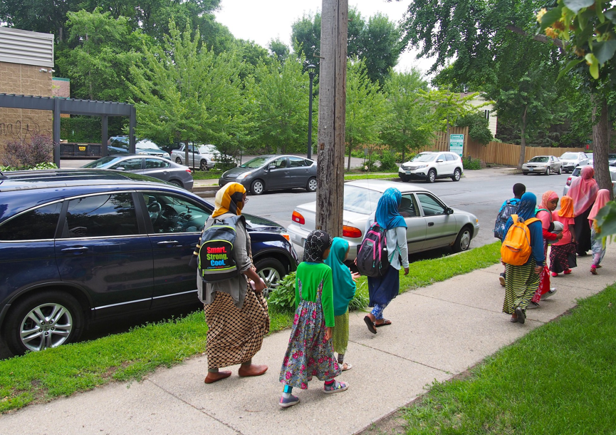 Children and adult walking on sidewalk