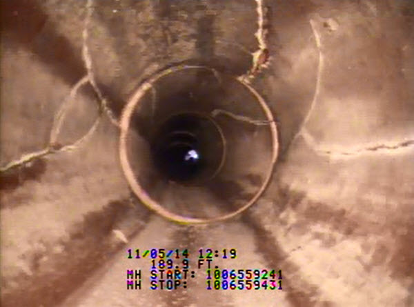 Interior view of storm pipe with cracks along the pipe's length.