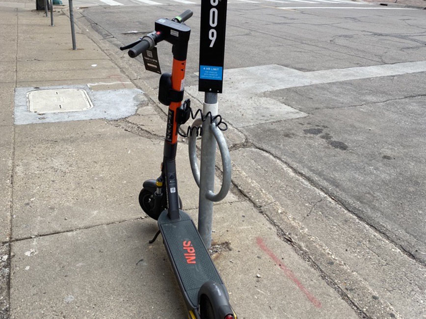 A scooter locked to a pole.