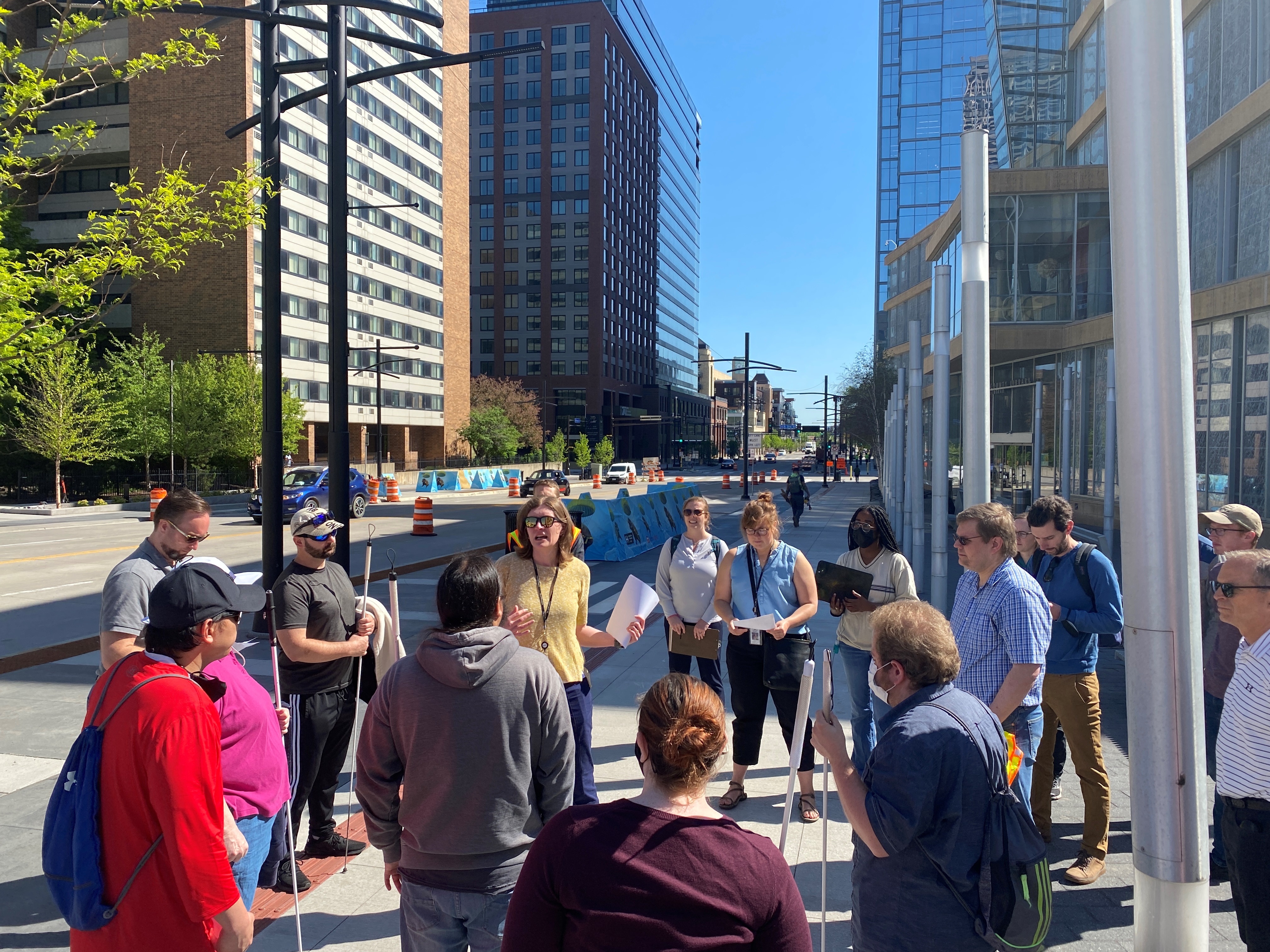 A group of people standing on the sidewalk in downtown Minneapolis discussing the tactile edge on 4th St S