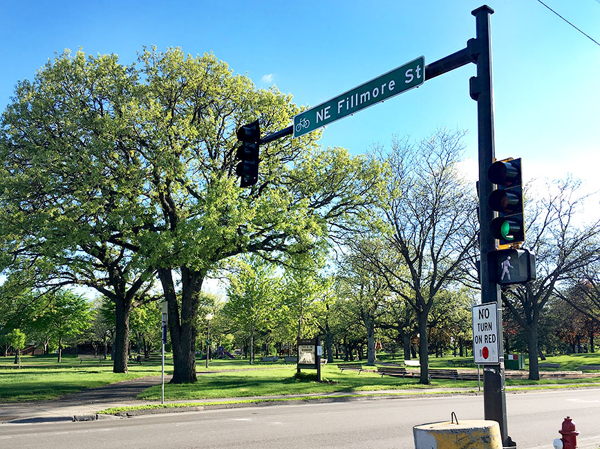 Street with traffic signal above and trees along the side