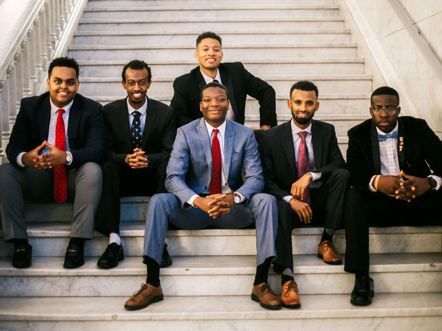 Group of Scholars in suits sitting on stairs.