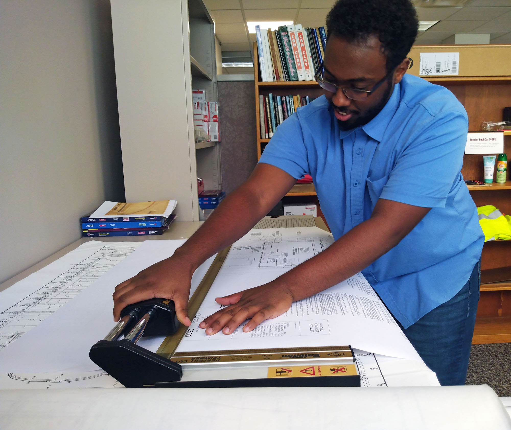 An intern studies building plans in an office.