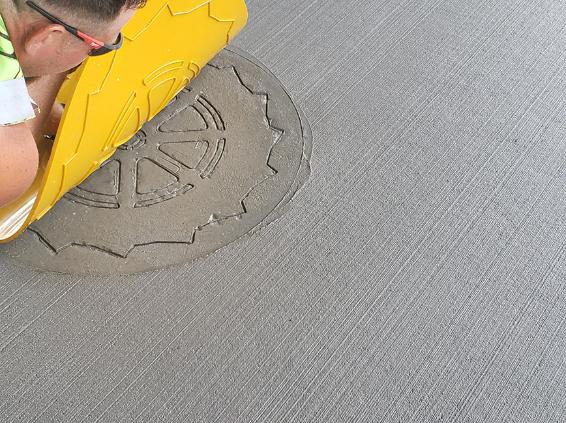 Worker stamping a design into a sidewalk
