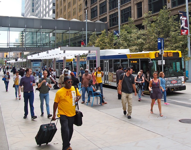 People walking downtown by a bus