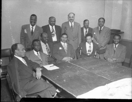 A group of African American civic leaders gathered at a table A group of African American civic leaders gathered at a table