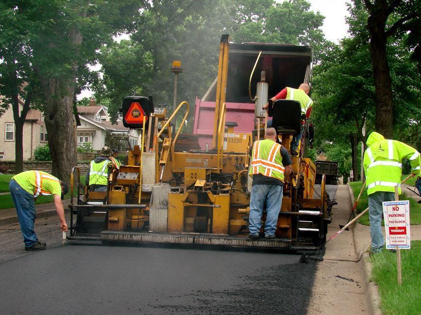 City staff using machine to lay fresh asphalt on a street
