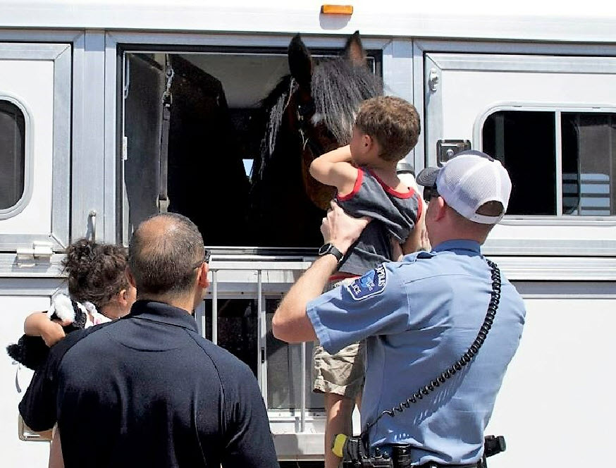 Police holding a child to see horse