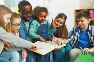 Group of children reading a book with teacher Group of children reading a book with teacher
