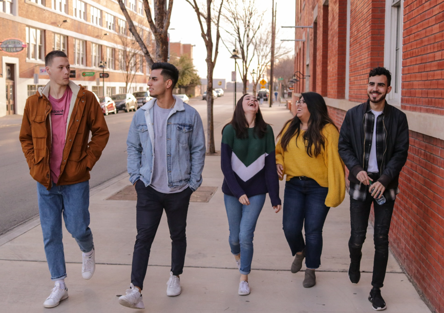 Five high school students walking abreast on a sidewalk