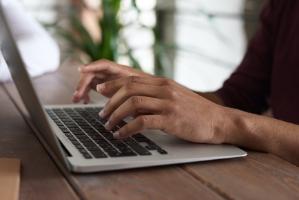 Hands typing at laptop
