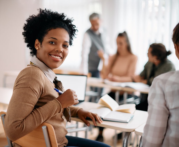 Smiling person at table with books