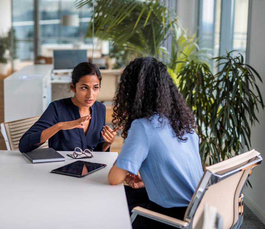 A person at an office table explaining something to another. A person at an office table explaining something to another.