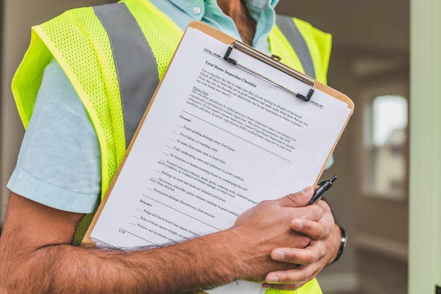 Person with yellow vest holding clipboard