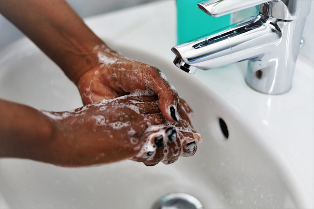 Person's hands washing with soaps under water faucet