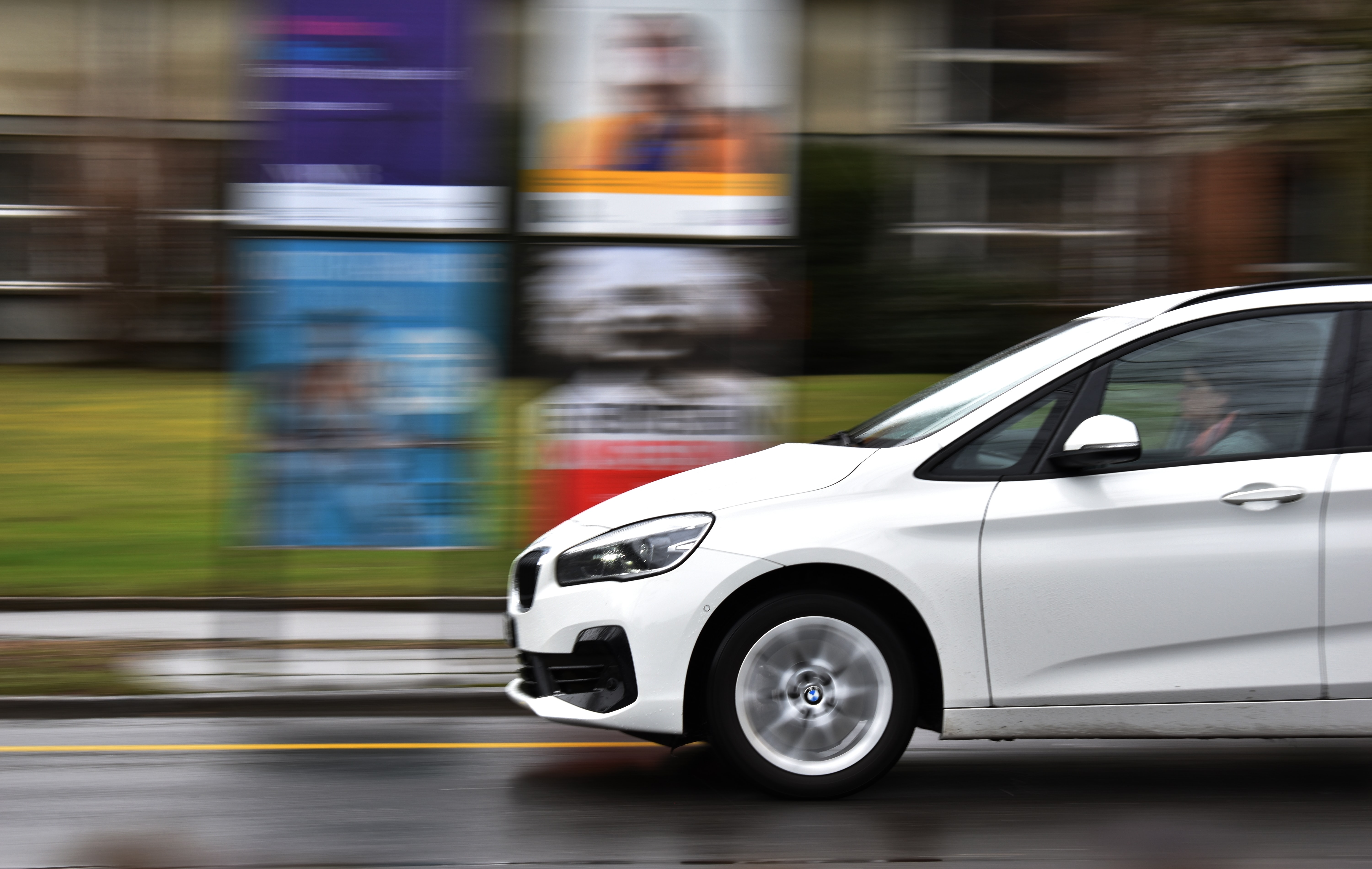 The front of a moving car with the blur of signs and buildngs in the background