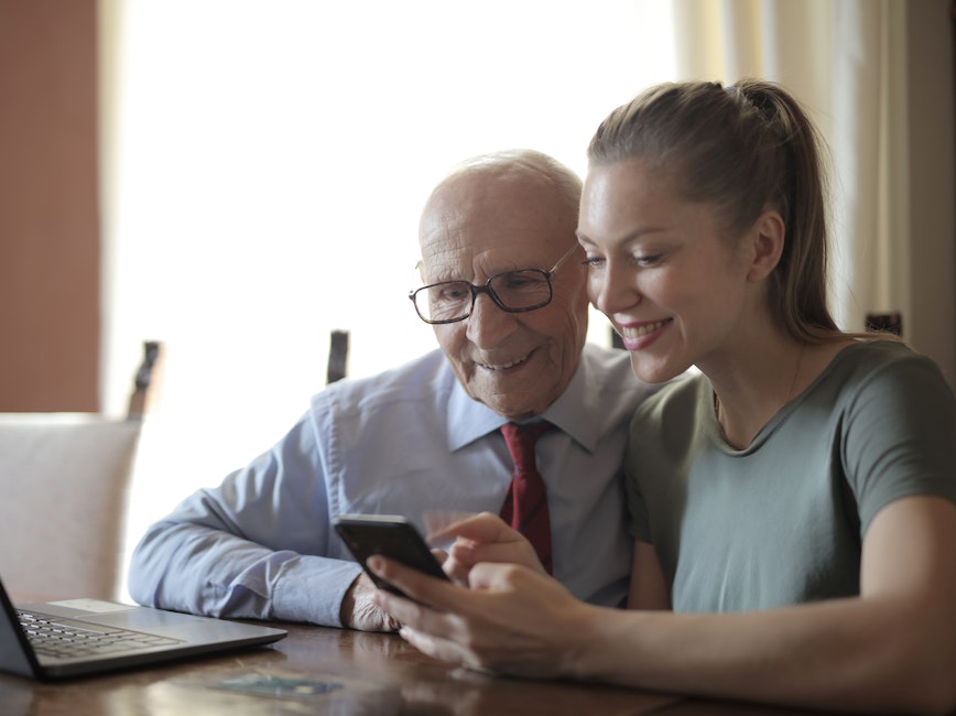 Elderly person and young person using computer and cellphone Elderly person and young person using computer and cellphone