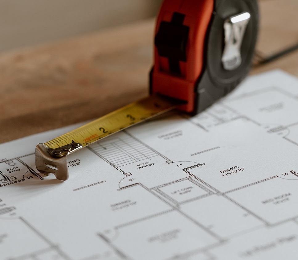 Blueprint on a table with a tape measure and pen