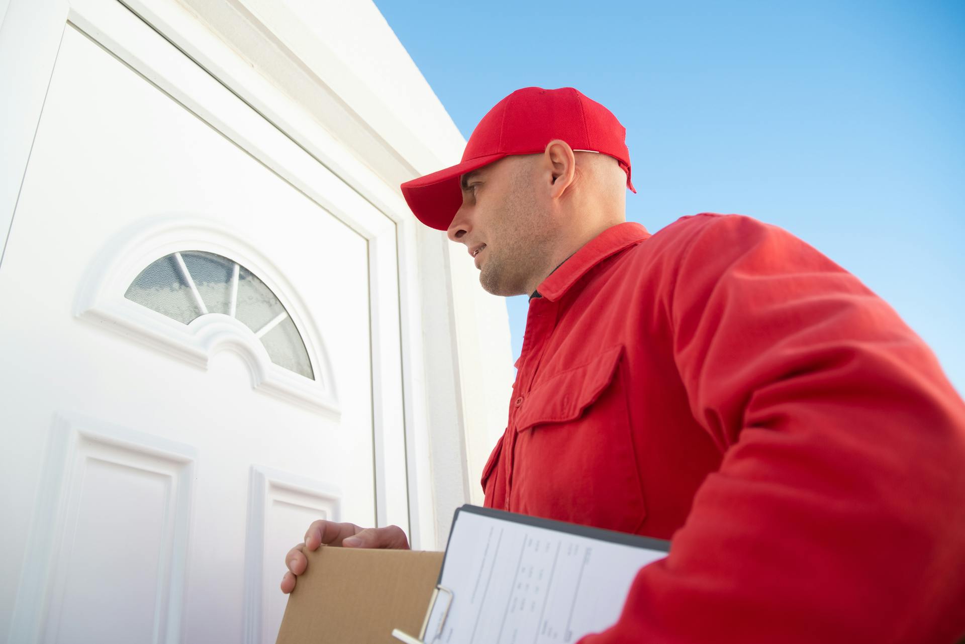 Person in red jacket standing beside white door