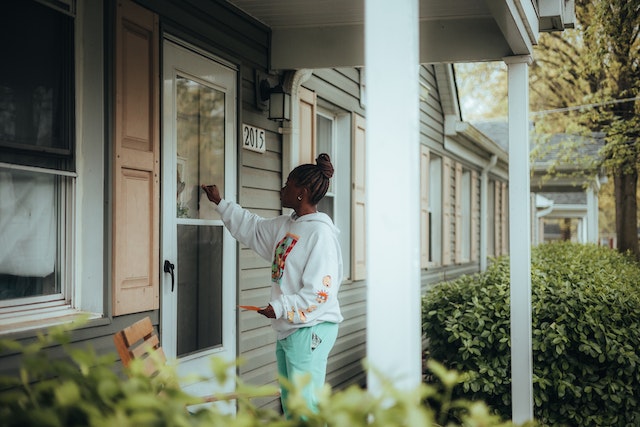 Person in front of house knocking on front door.