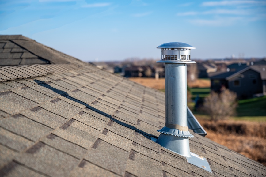 silver vertical vent near the peak of a shingled roof