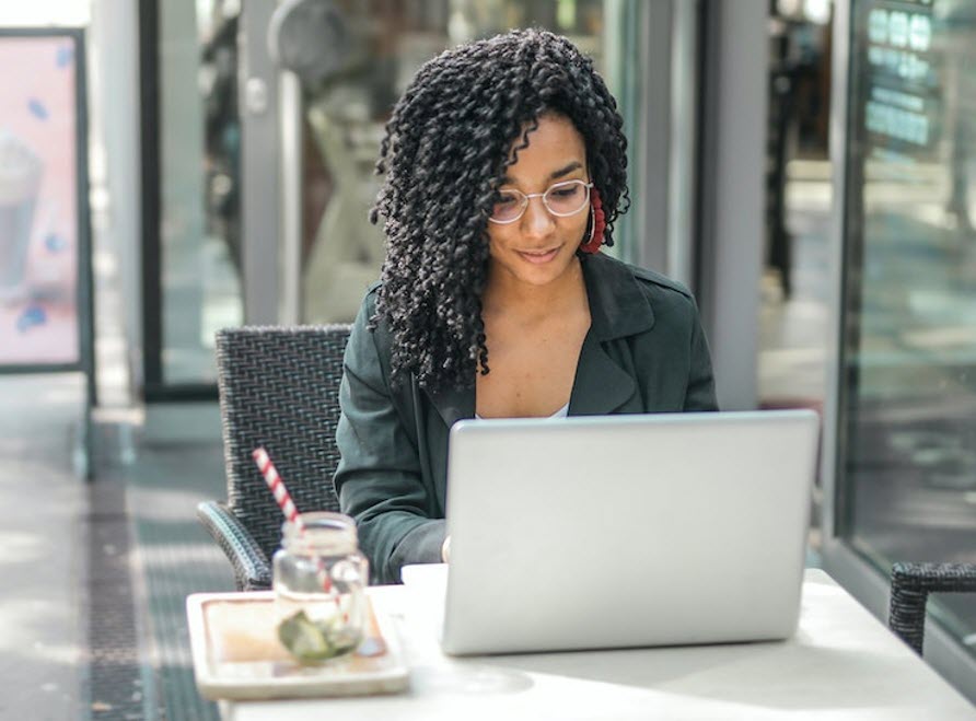 woman on laptop outdoors with drink